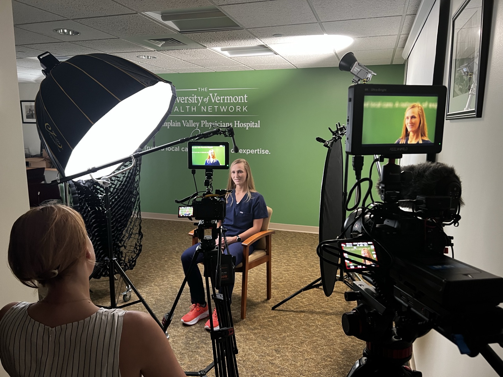 JGI Media filming an on-location interview with two cameras, a boom microphone, and a softbox light