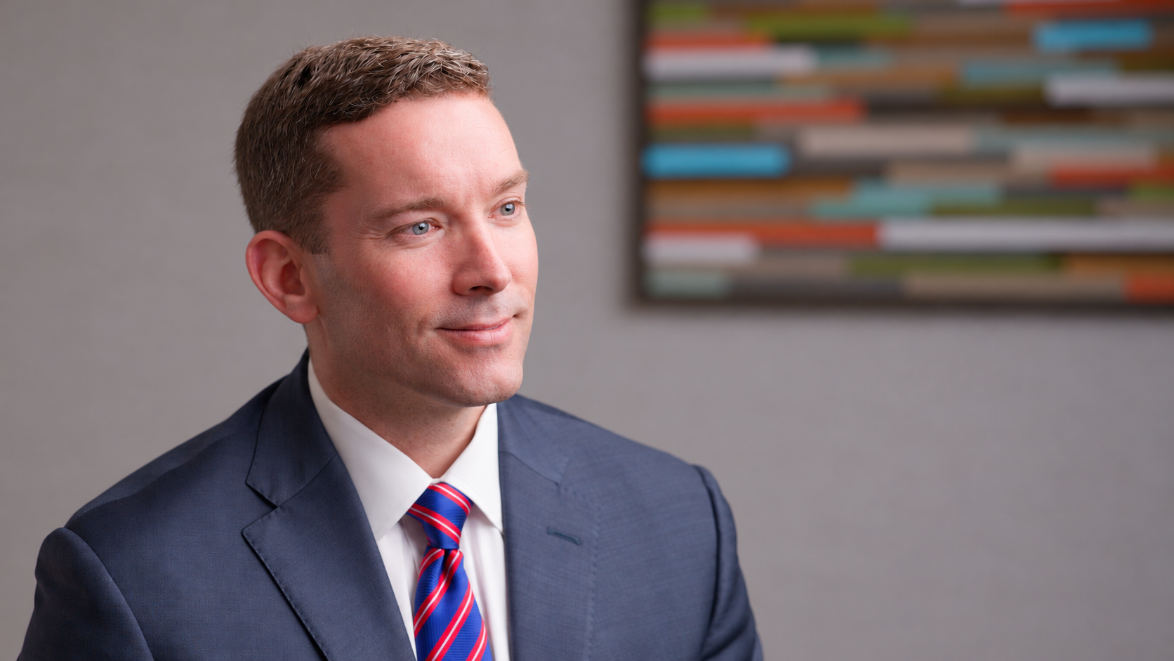 Interview portrait of Mike in a navy suit and striped tie.